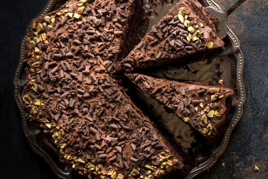 bolo com ganache e raspas de chocolate por cima, com pistache em volta