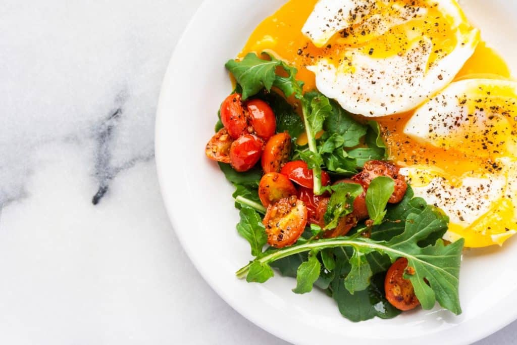 Ovos de gema mole com salada de rúcula e tomate um almoço com nutrientes e sabor