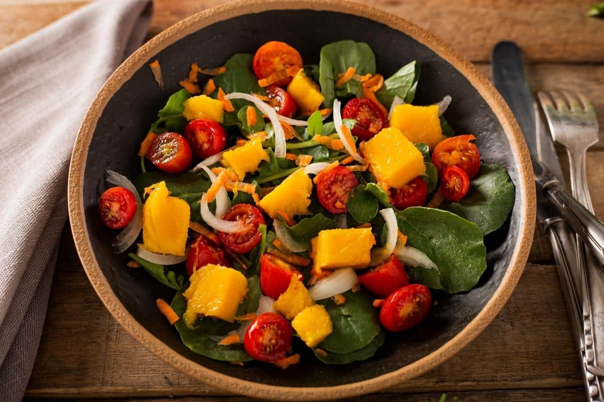 Salada tropical de agrião com tomates cereja manga e cebola um toque de sabores no prato