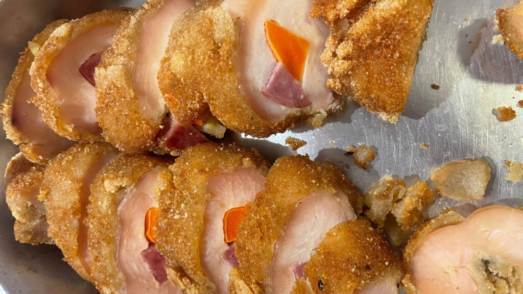 Enrolado de frango empanado com pedaços de bacon e cenoura